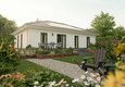 Effizienter Bungalow 110 mit Photovoltaik-Anlage auf dem Walmdach, moderner Terrasse und grünem Garten