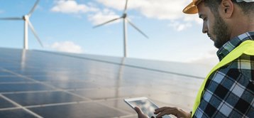 energie-sparen-haus-solar-photovoltaik-foerderung-07 Mann vor Solaranlage und Windrädern