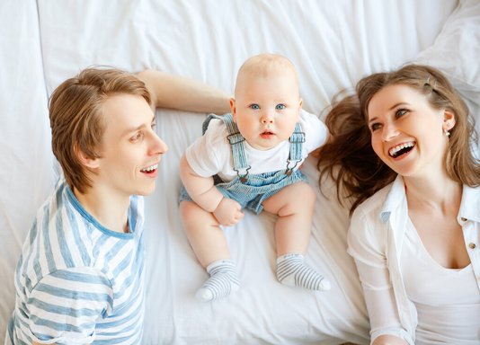 Haus-Familie-Wohnen-Serie-2 Mutter, Vater und Kind liegen auf dem Bett.